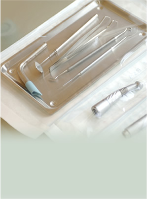 金属製のトレイの上に、鏡、プローブ、ドリルを含む滅菌済みの歯科器具一式が用意された写真。