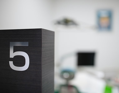 木目調のダークカラーの仕切り壁に「5」の数字が表示された診療室の写真。